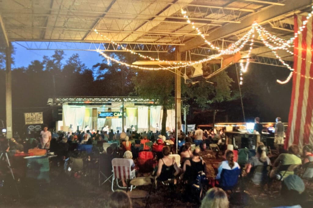 A vintage photo of participants at an outdoor concert at Stone Man Park's Greenfield Excursion stage. A banner on the stage reads "Music Camp 2009"