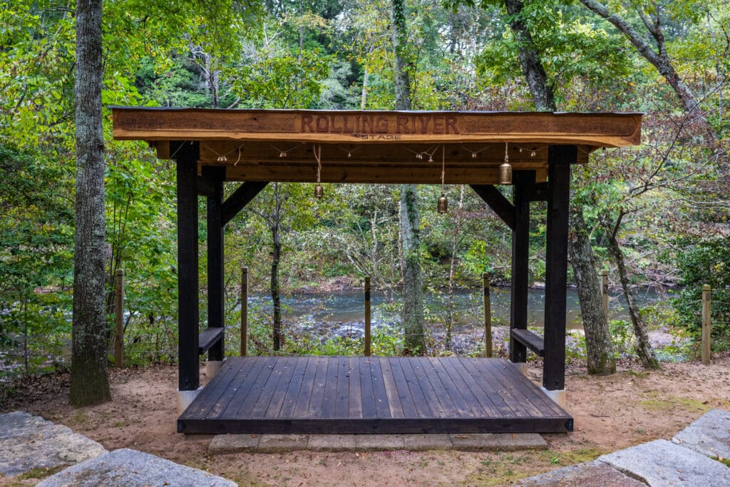 The "Rolling River" stage: a small, wooden structure with a view of the Pacolet River behind it