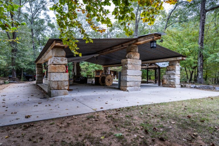 A large pavilion crafted from large stones and repurposed metal beams