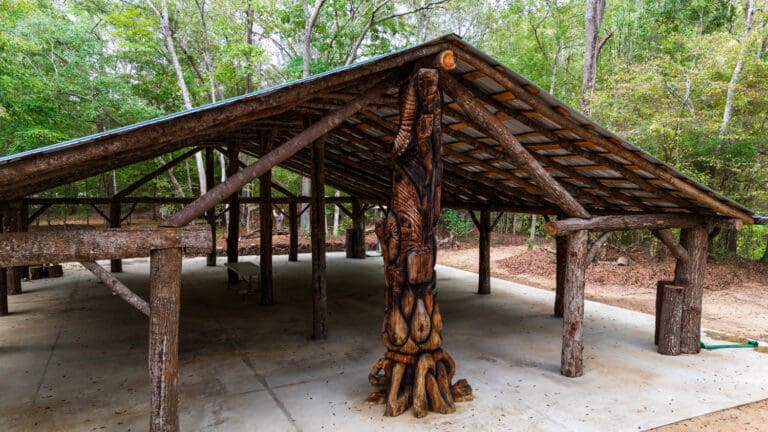 Under Oaks Pavillion, the structure is seen with a large carved totem in the middle, with its structure being made of large logs with the bark still attached